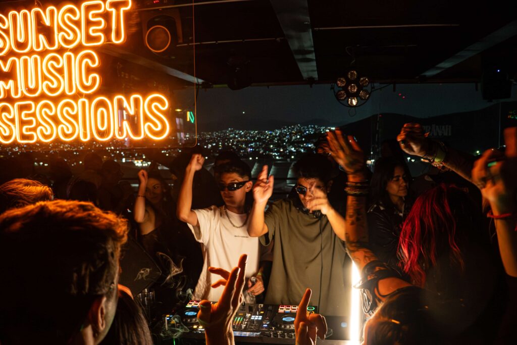 Two DJs performing as people dance at night, with the surrounding landscape visible at PRANÄH in Zona Esmeralda.